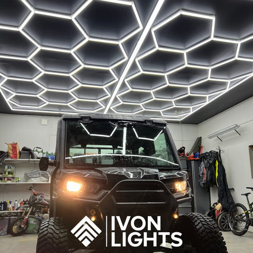 Två armaturer från IVON Hexagon Garagebelysning 2-pack monterade på ett svart tak, för ett kraftfullt ljusflöde.